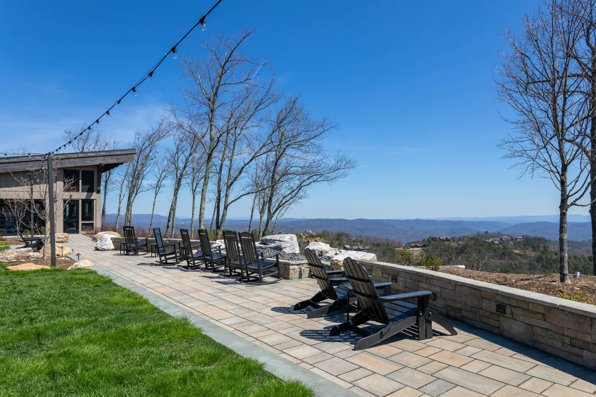 A welcoming patio area with inviting outdoor seating that looks out across expansive mountain views. String lights and gentle outdoor lighting add ambiance, making the space ideal for gathering at any time of day or evening.